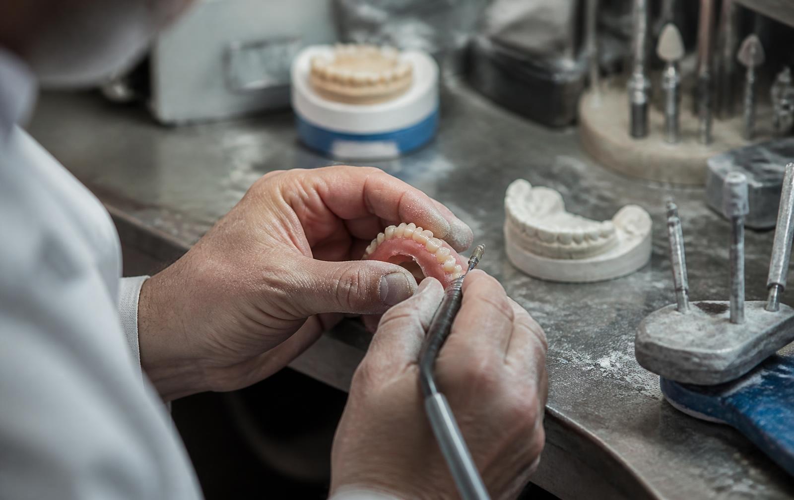 Técnico del Laboratorio Dental A.G. trabajando manualmente sobre una prótesis dental